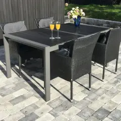 En vacker stenlagd uteplats med ett mörkt matbord och stolar, perfekt för inspiration. Två glas med apelsinjuice står redo.