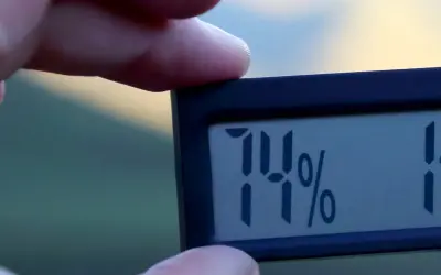 En digital hygrometer visar 74%, vilket indikerar hög luftfuktighet inomhus.
