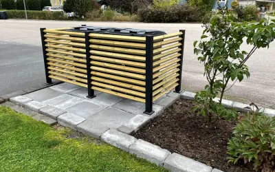 Snyggt insynsskydd för att bygga in soptunnor. Trälameller och svarta stolpar ger ett modernt utseende.