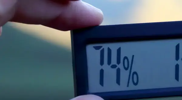 En digital hygrometer visar 74%, vilket indikerar hög luftfuktighet inomhus.