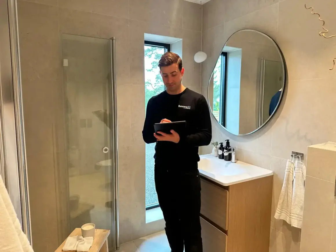 Man med surfplatta i ett modernt badrum, redo för renovering badrum.