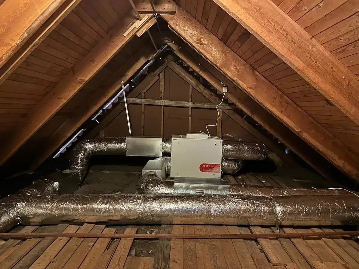 FTX-installation i en vind med isolerade ventilationsr&ouml;r och en vit enhet.