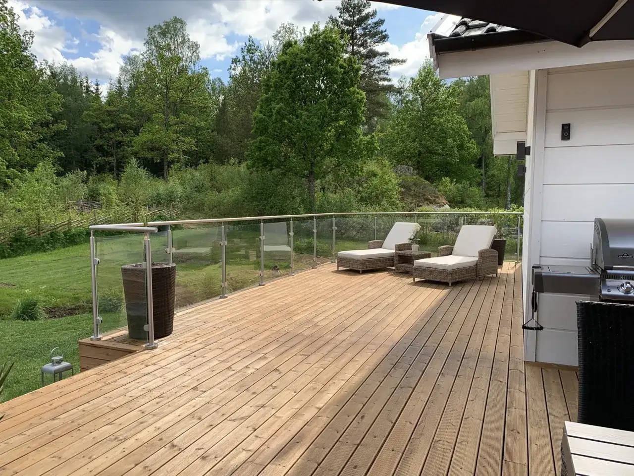 Solig altan med oljad träyta, perfekt temperatur för att njuta av naturen. Två solstolar står redo.